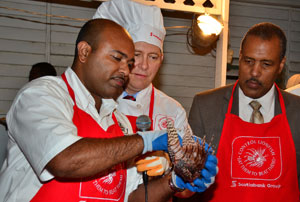 President and Chief Executive Officer, Scotiabank, Bruce Bowen (second left) and Pro Vice Chancellor and Principal, University of the West Indies’ (UWI), Mona Campus, Professor Gordon Shirley (right) observe as National Lion Fish Project Lead, Dr. Dayne Buddo (left) demonstrates how to properly prepare the lionfish for consumption.